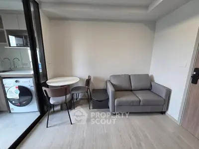 Modern living room with compact dining area and washing machine in view.