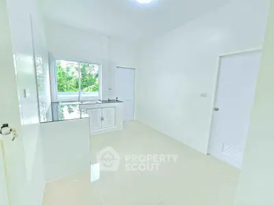 Bright and modern kitchen with sleek white cabinetry and large window view.