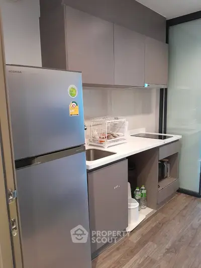 Modern compact kitchen with sleek cabinetry and stainless steel fridge