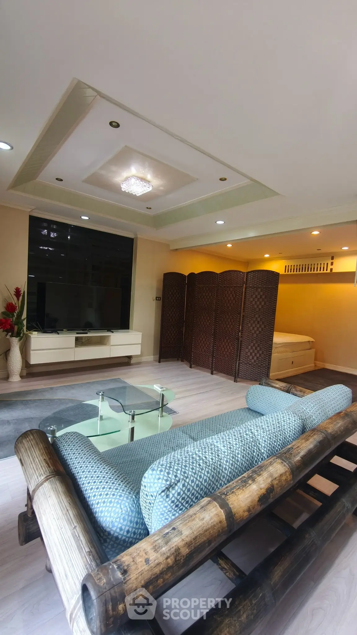 Spacious living room with modern decor and bamboo furniture, featuring a cozy ambiance and elegant ceiling design.