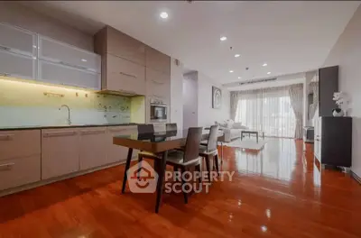 Spacious open-layout kitchen and living room with elegant wooden flooring and modern furniture.