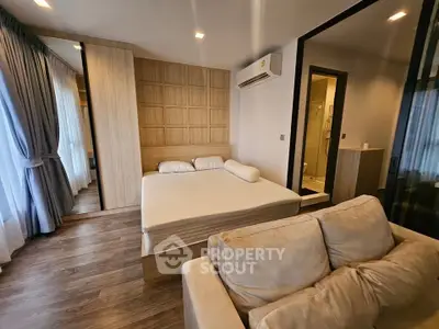 Modern bedroom with wooden accents, cozy sofa, and ensuite bathroom in a stylish apartment.