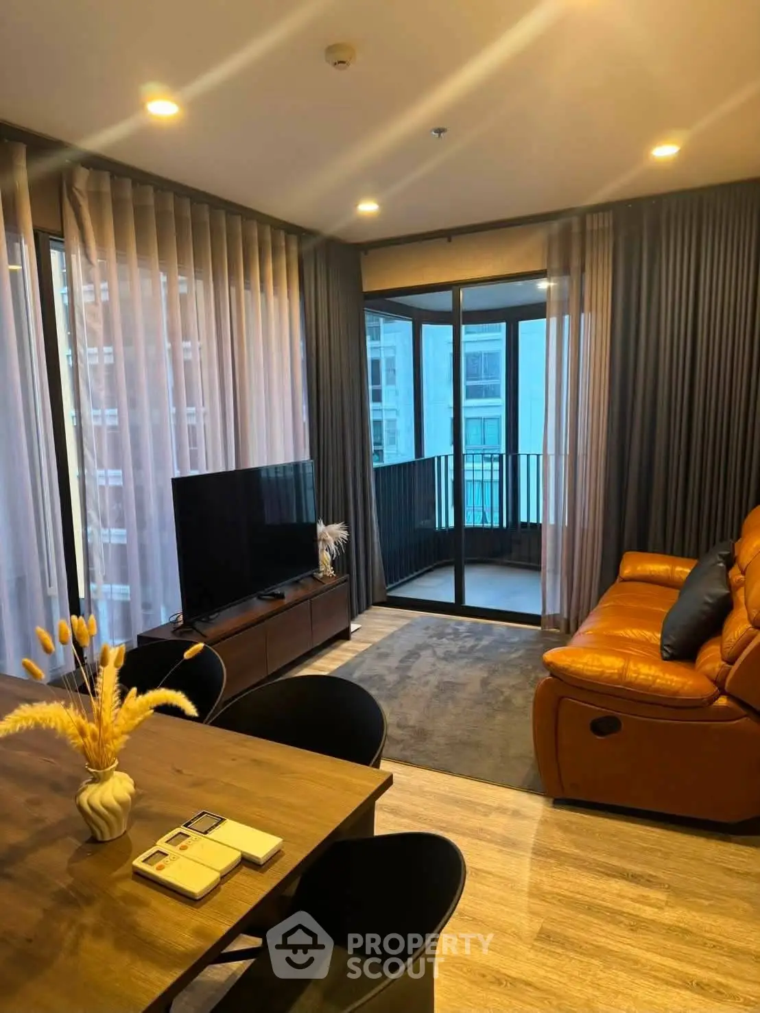 Modern living room with leather sofa and balcony view in high-rise apartment