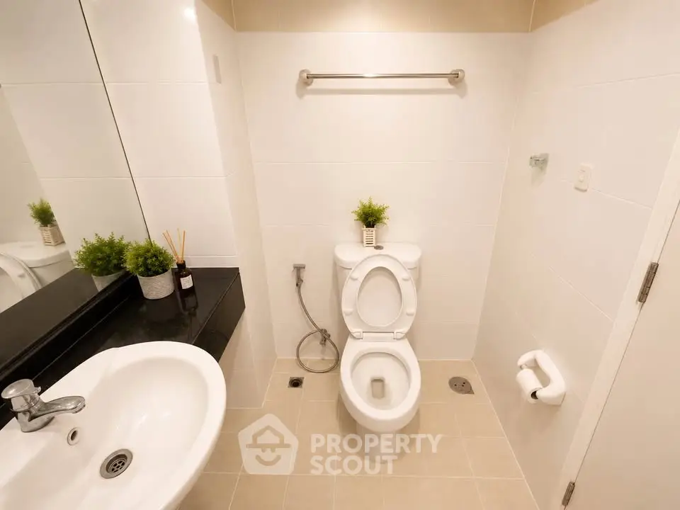 Modern bathroom with sleek fixtures and minimalist design, featuring a white toilet and sink.