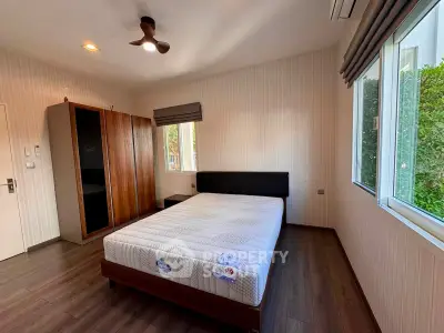 Spacious bedroom with large windows and modern furnishings in a stylish home.
