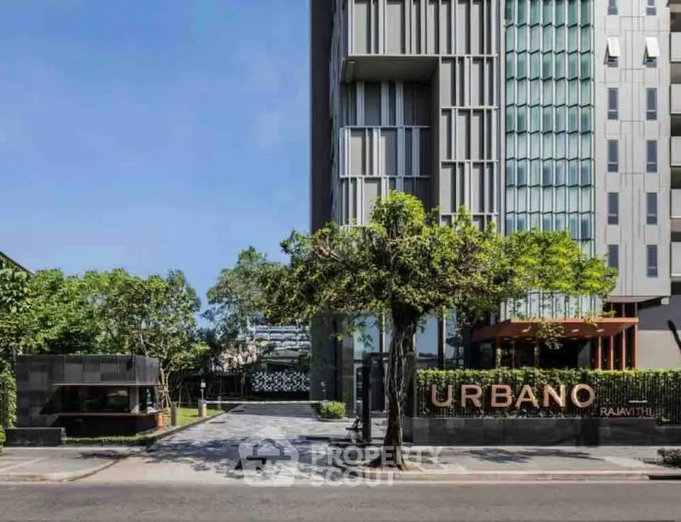 Modern urban condominium with sleek architecture and lush greenery at entrance.
