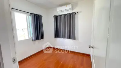 Spacious empty bedroom with wooden flooring and air conditioning, ready for customization.