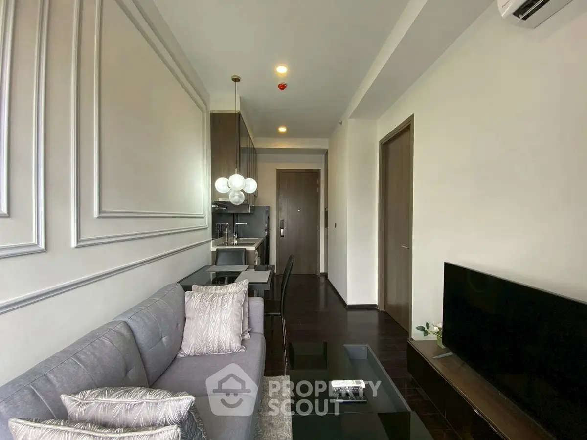 Modern living room with sleek furniture and open kitchen layout in a stylish apartment.