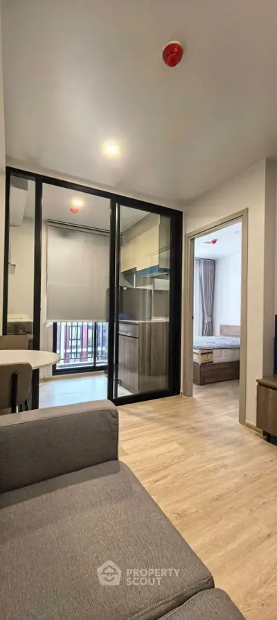 Modern apartment interior with open layout, featuring a cozy living room and a glimpse of the bedroom.