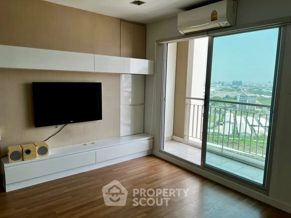Modern living room with balcony and city view, featuring sleek TV setup and air conditioning.