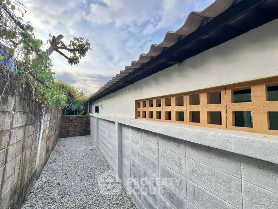 Charming exterior view of a modern building with gravel pathway and lush greenery.
