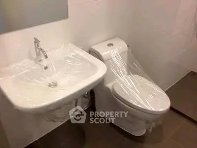 Modern bathroom with sink and toilet wrapped in protective plastic