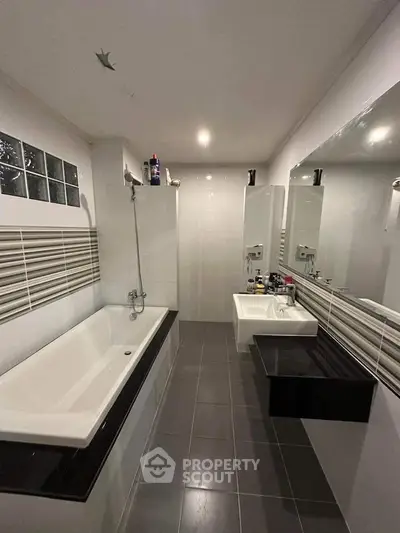 Modern bathroom with sleek design, featuring a bathtub and stylish fixtures.