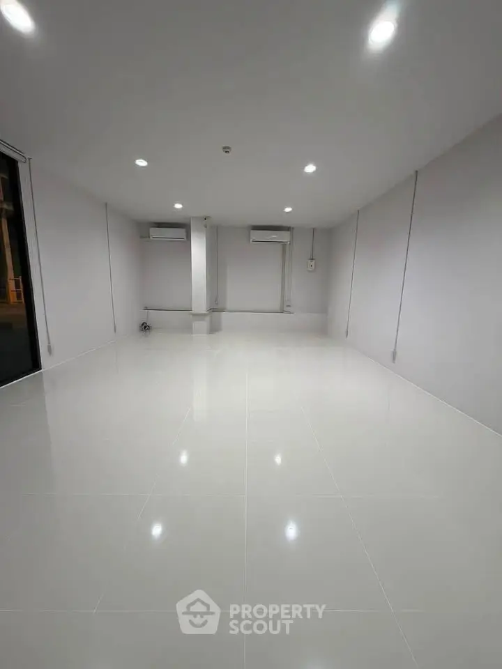 Spacious empty room with glossy white tiles and modern lighting, ideal for customization.
