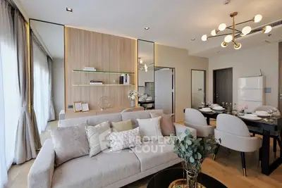 Modern living room with elegant decor and open dining area, featuring stylish lighting and cozy seating.