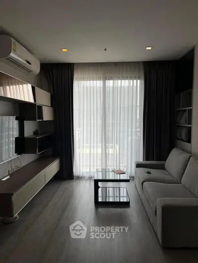 Modern living room with sleek furniture and large window, perfect for relaxation and entertainment.