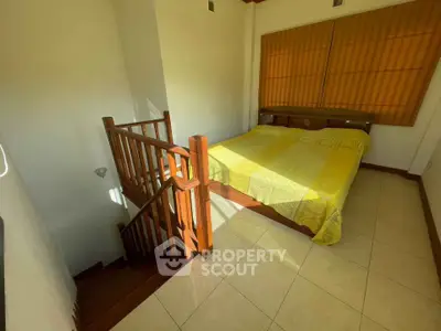 Cozy bedroom with wooden staircase and bright yellow bedding, perfect for a warm and inviting atmosphere.