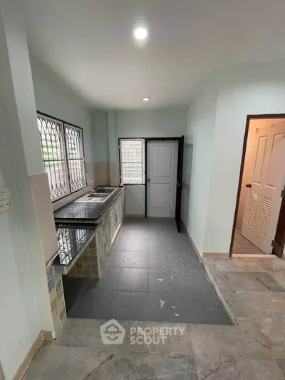 Spacious kitchen with tiled flooring and ample natural light, featuring a double sink and modern fixtures.