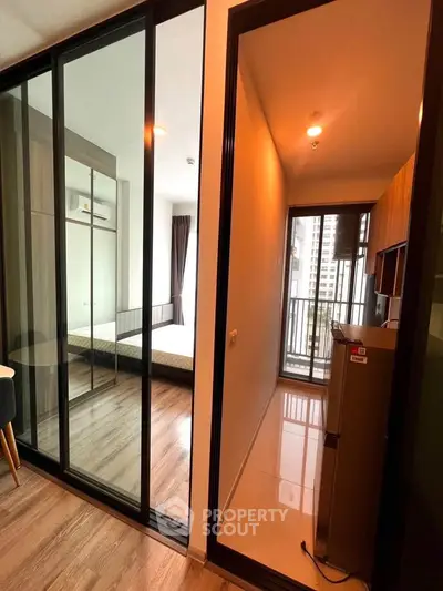 Modern apartment interior with glass partition, wooden flooring, and balcony view.