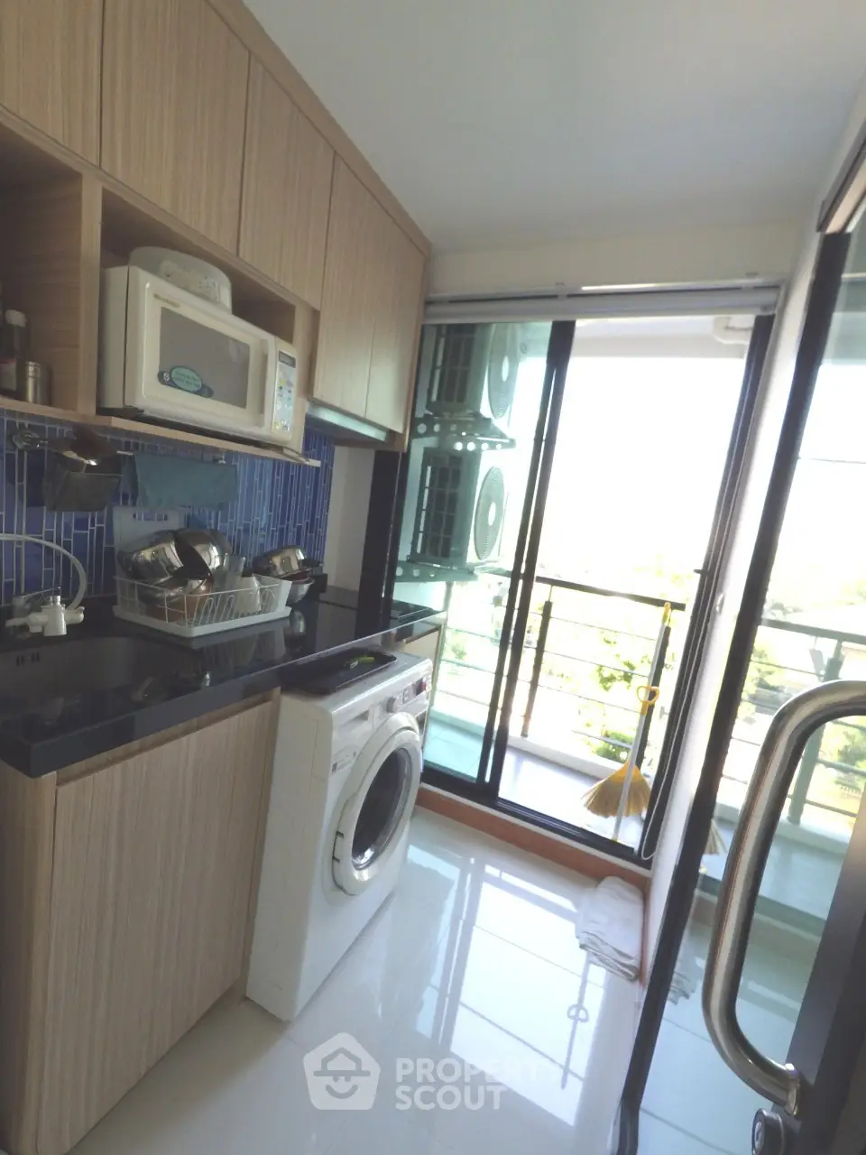 Modern kitchen with washing machine and balcony view in stylish apartment.