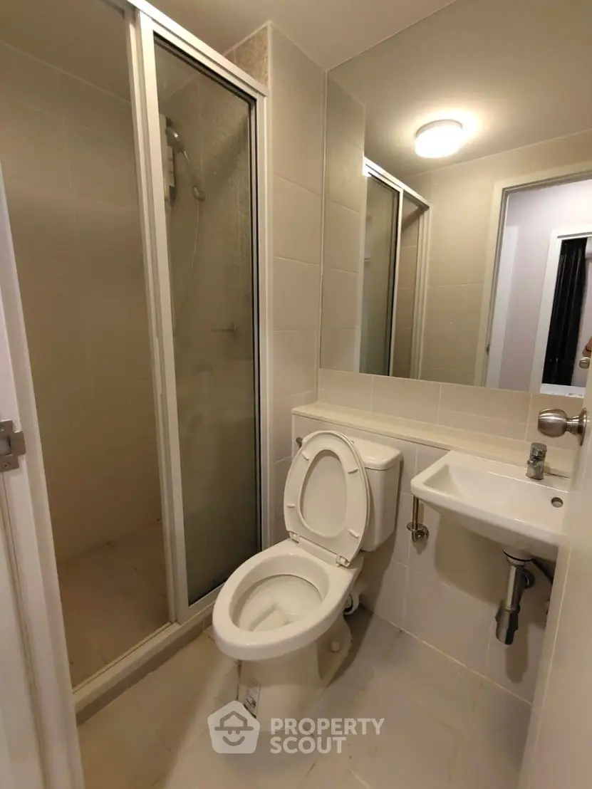 Modern compact bathroom with shower and toilet in sleek design.