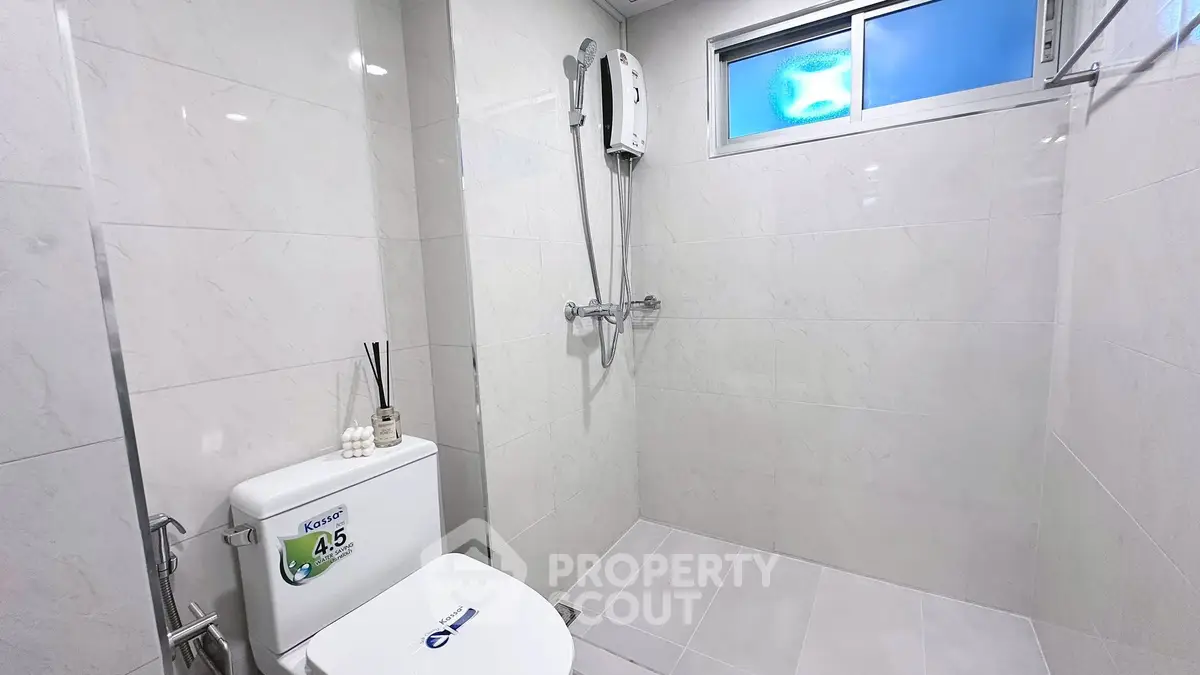 Modern bathroom with sleek shower and toilet in bright, minimalist design.