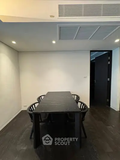 Modern dining area with sleek black table and chairs, minimalist design, and recessed lighting.
