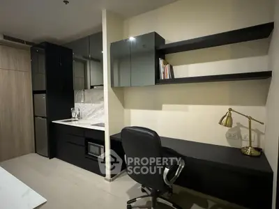 Modern study area with sleek black desk and shelves, adjacent to a compact kitchen.