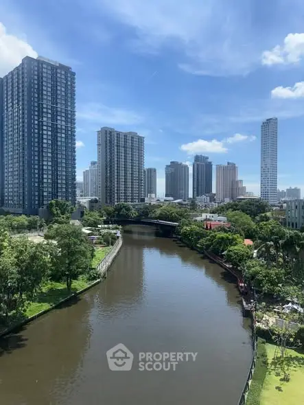 Stunning cityscape view with river and modern high-rise buildings under a clear blue sky.