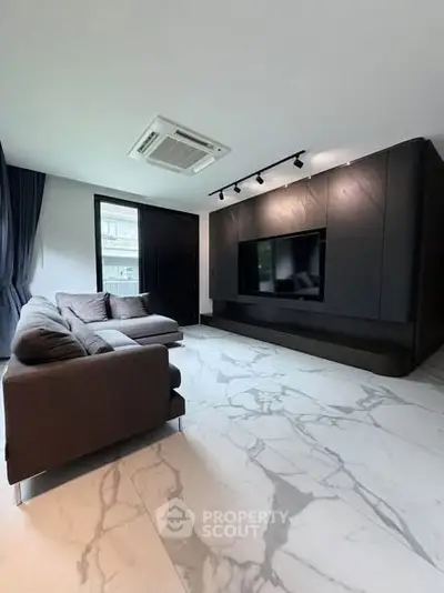 Modern living room with sleek black entertainment wall and marble flooring
