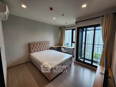 Modern bedroom with large windows and city view, featuring a stylish bed and balcony access.
