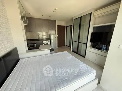 Modern studio apartment with compact kitchen and cozy sleeping area, ideal for urban living.