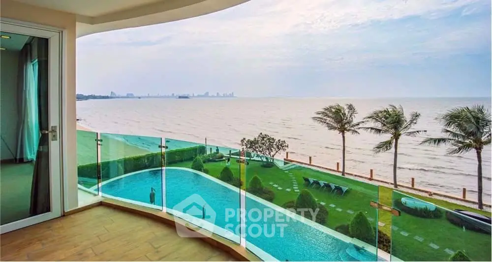 Stunning oceanfront view from a luxury balcony overlooking a pool and lush garden.