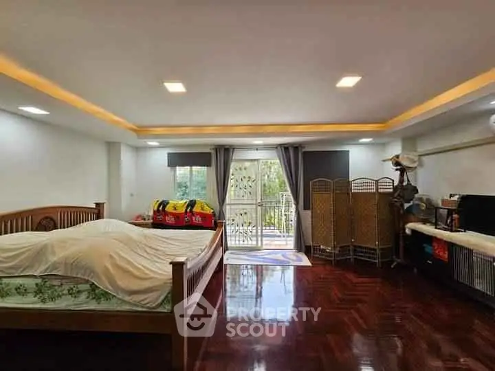 Spacious bedroom with wooden flooring and balcony access, perfect for relaxation.