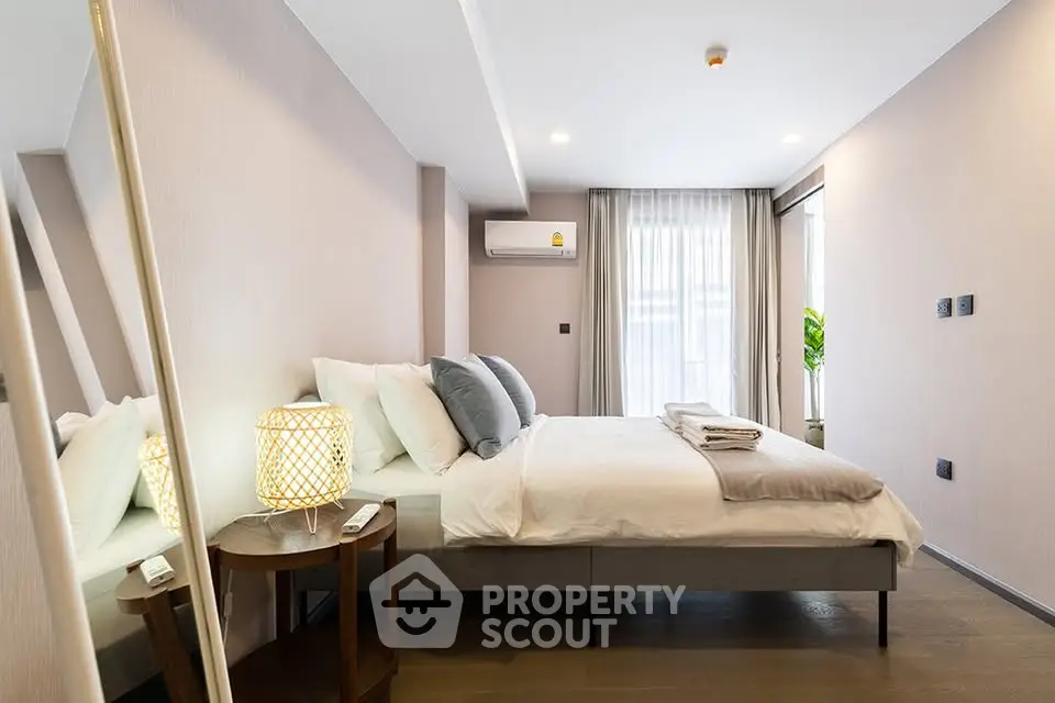 Modern bedroom with stylish decor and natural light, featuring a cozy bed and elegant furnishings.