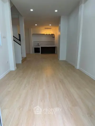 Spacious open-plan living area with modern kitchen and elegant lighting.