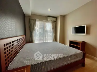 Spacious bedroom with modern decor and large window offering natural light.