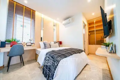 Modern bedroom with stylish decor and natural light, featuring a cozy bed and workspace.