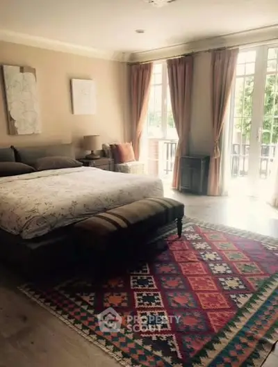 Spacious bedroom with elegant decor and large windows offering natural light.