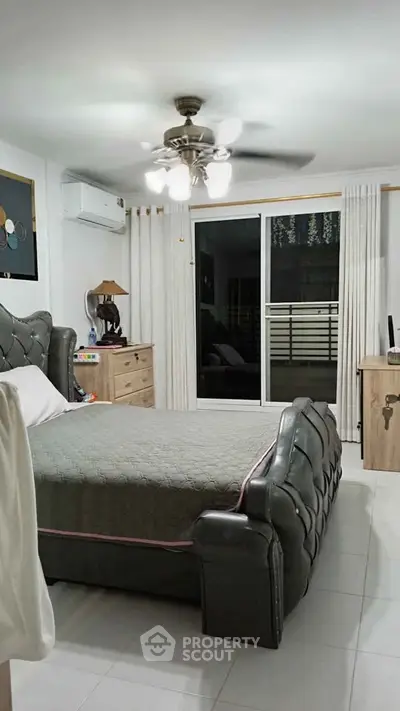 Spacious bedroom with elegant decor and balcony access in modern apartment.