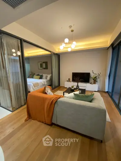 Modern living room with cozy sofa and stylish decor, open layout leading to a chic bedroom.