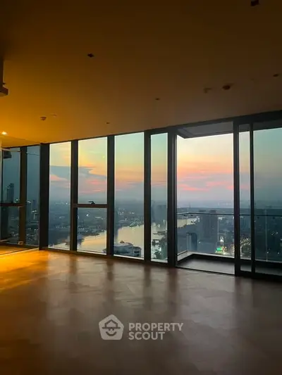 Luxurious high-rise apartment with stunning sunset city view through floor-to-ceiling windows.
