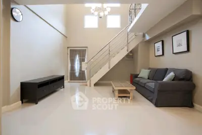 Spacious modern living room with high ceiling and stylish staircase