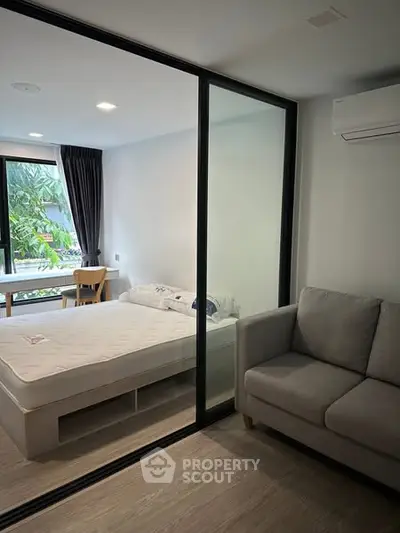 Modern studio apartment with glass partition, cozy bed, and sofa, ideal for urban living.