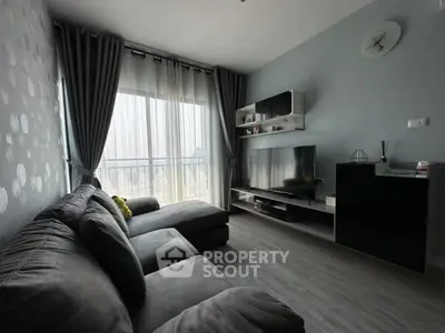 Modern living room with large sofa and TV, featuring stylish decor and natural light.