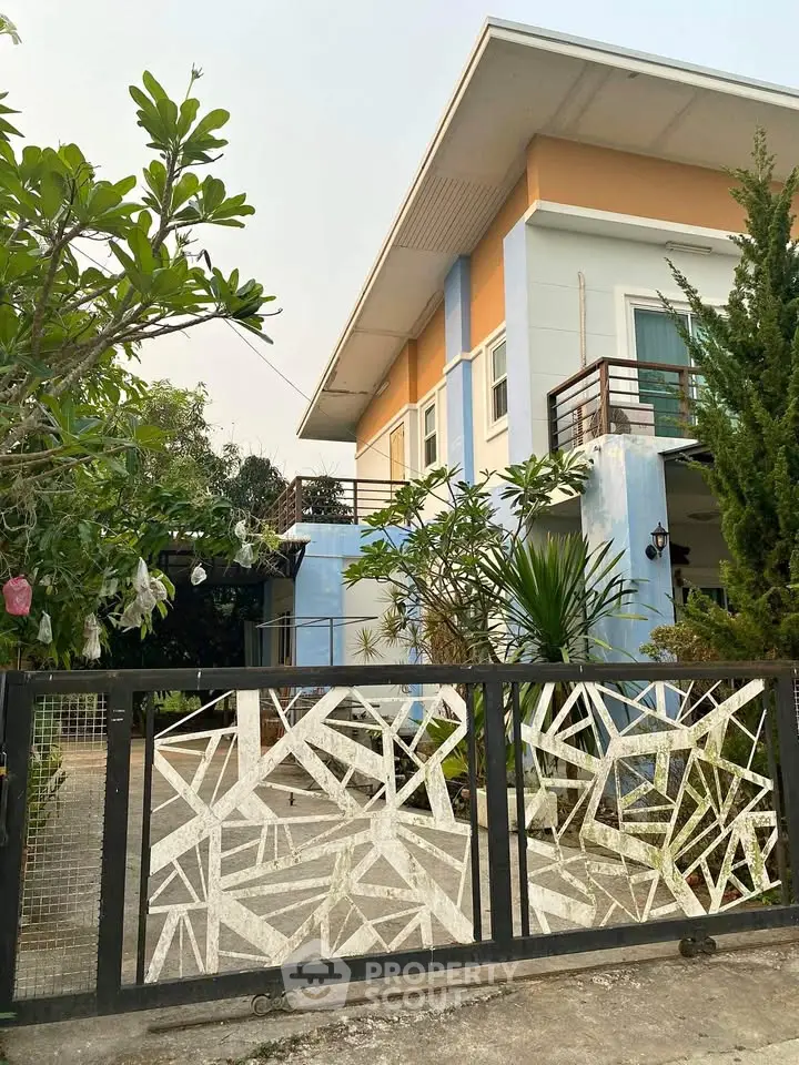 Modern two-story house with unique geometric gate and lush greenery