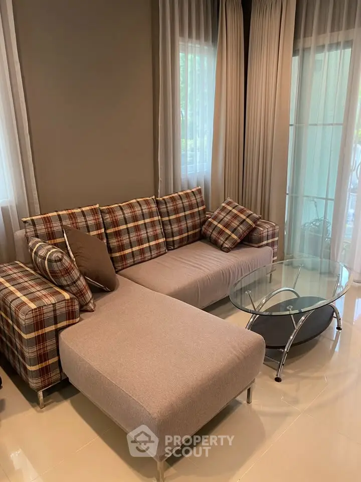 Cozy living room with stylish plaid sofa and modern glass coffee table, perfect for relaxation.