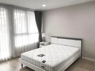 Spacious bedroom with large window and modern furnishings in a stylish apartment.