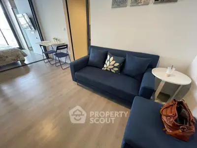 Modern living room with blue sofa and open layout to bedroom