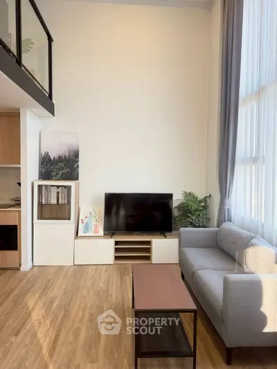 Modern living room with high ceiling, large windows, and stylish furniture in a contemporary apartment.